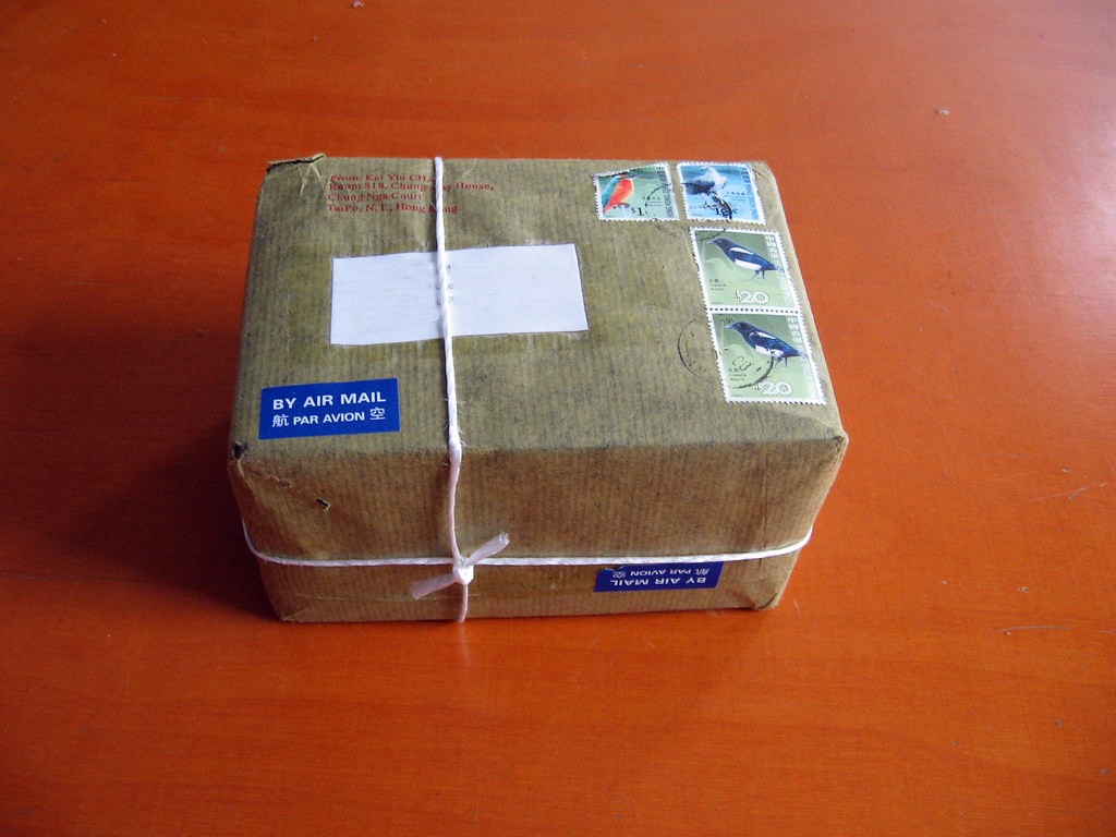 항공우편(BY AIR MAIL) 스티커와 우표가 붙은 갈색 종이 포장 국제 소포 — 해외에서 배송된 택배 상자